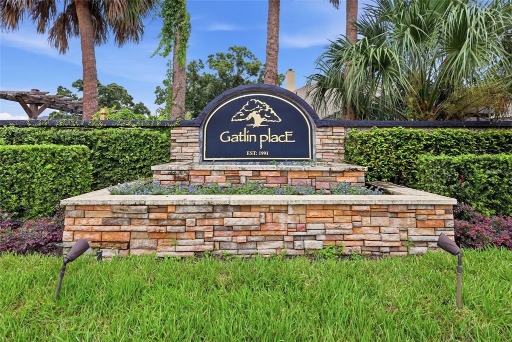 A stone monument sign for Gatlin Place stands in front of a hedge and palm trees — 3716 GATLIN PLACE CIRCLE, ORLANDO, FL