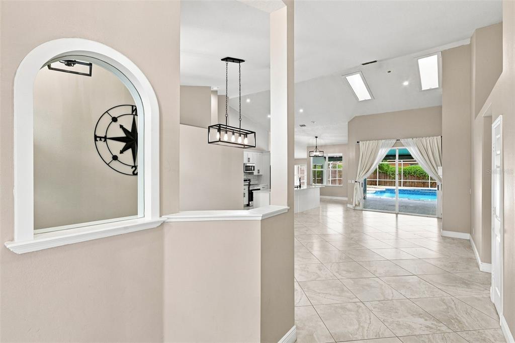 A view through an arched interior window into a bright living area with a pool — 3716 GATLIN PLACE CIRCLE, ORLANDO, FL