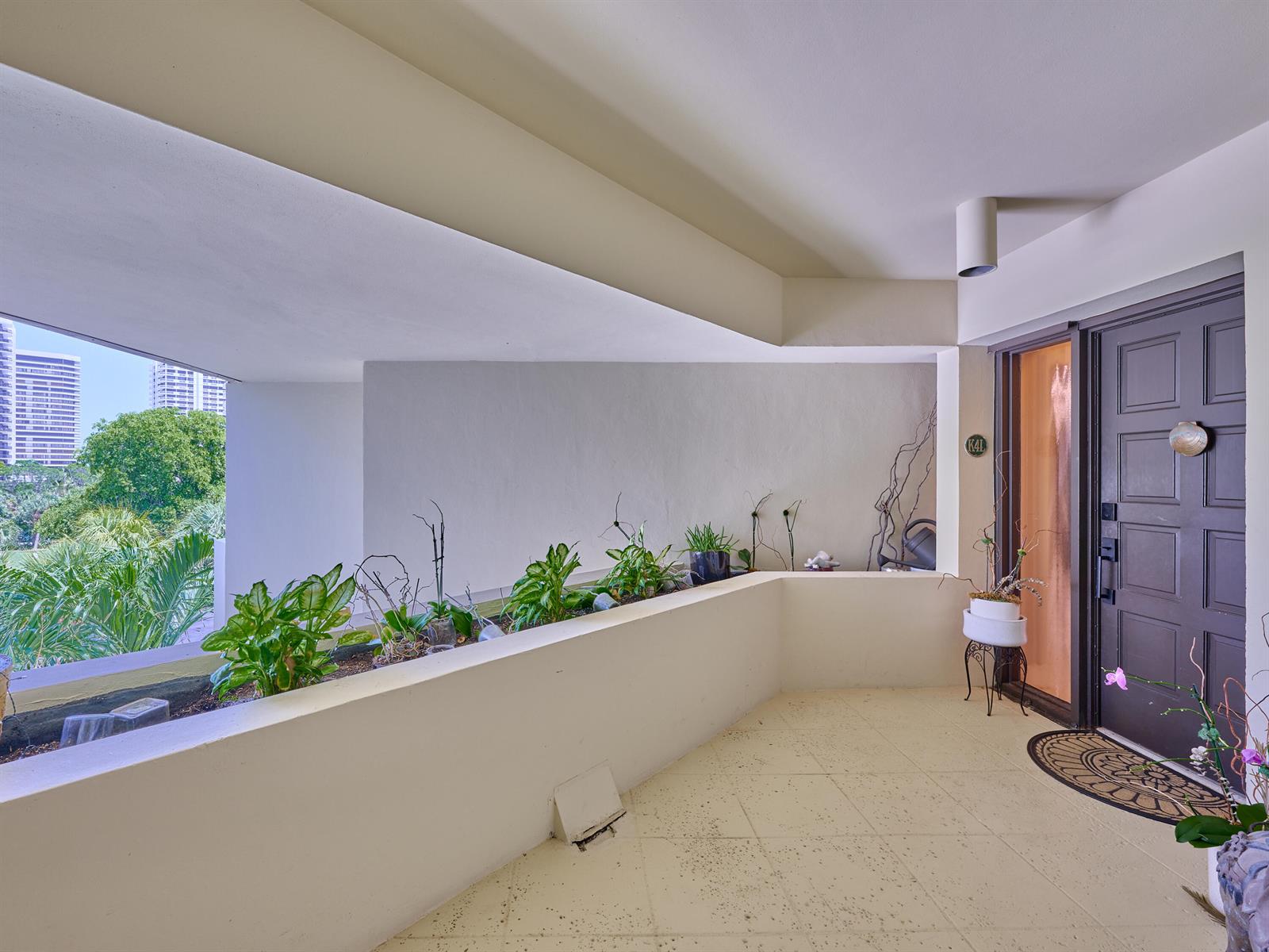 A covered balcony features a built-in planter, tiled flooring, and a dark brown entry door — 1117 Marine Way E, North Palm Beach FL 33408, NORTH PALM BEACH, FL