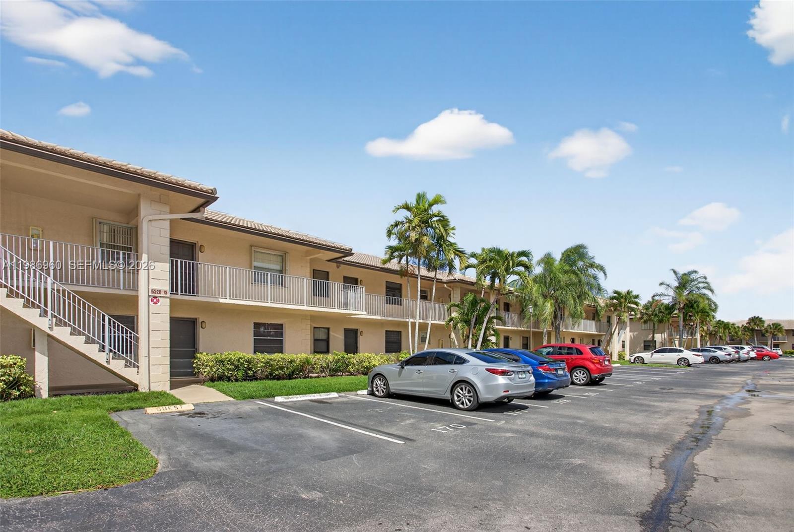 A two-story apartment building with a parking lot and palm trees under a blue sky — 5520 Lakeside Dr # 105, Margate FL 33063, MARGATE, FL