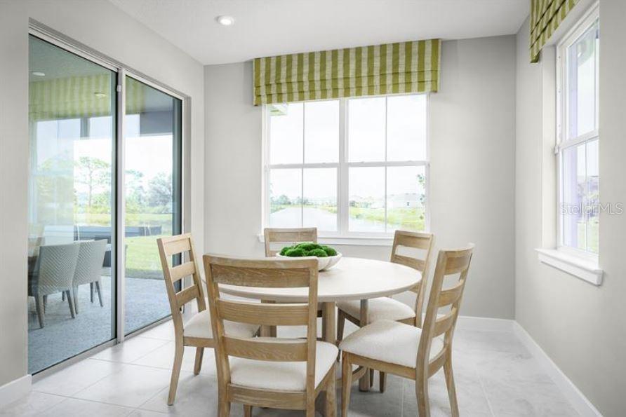 A dining area features a round table with four chairs, large windows, and sliding glass doors — 22141 PINE GROVE LOOP, LEESBURG, FL