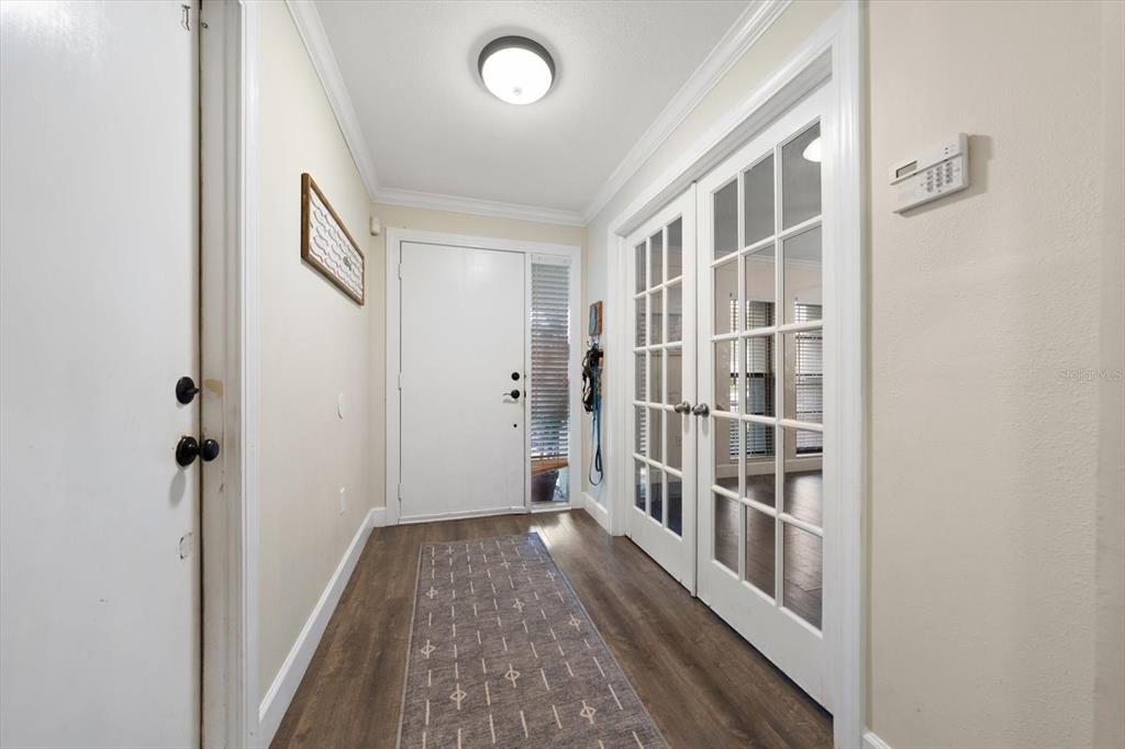 An entryway features wood-look flooring, a white front door, and glass-paned French doors — 521 MERAVAN DRIVE, PALM HARBOR, FL