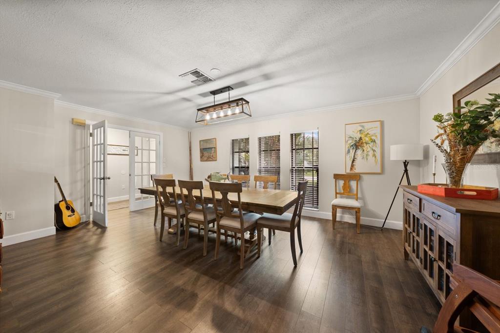 A dining room features a wooden table, six chairs, a chandelier, and dark wood flooring — 521 MERAVAN DRIVE, PALM HARBOR, FL