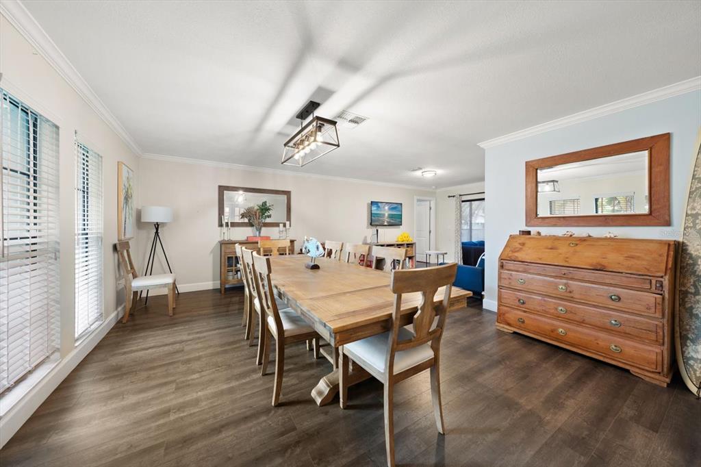 A dining room features a wooden table, chairs, a sideboard, and a large wall mirror — 521 MERAVAN DRIVE, PALM HARBOR, FL