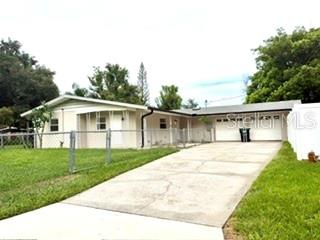 A single-story house with a white exterior, a concrete driveway, and a chain-link fence — 2410 LANDO LANE, ORLANDO, FL