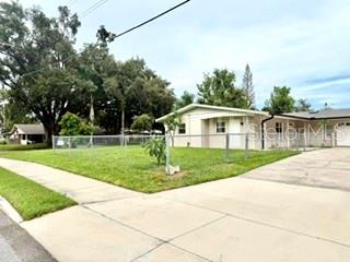 A single-story house with a light-colored exterior sits behind a chain-link fence on a lawn — 2410 LANDO LANE, ORLANDO, FL