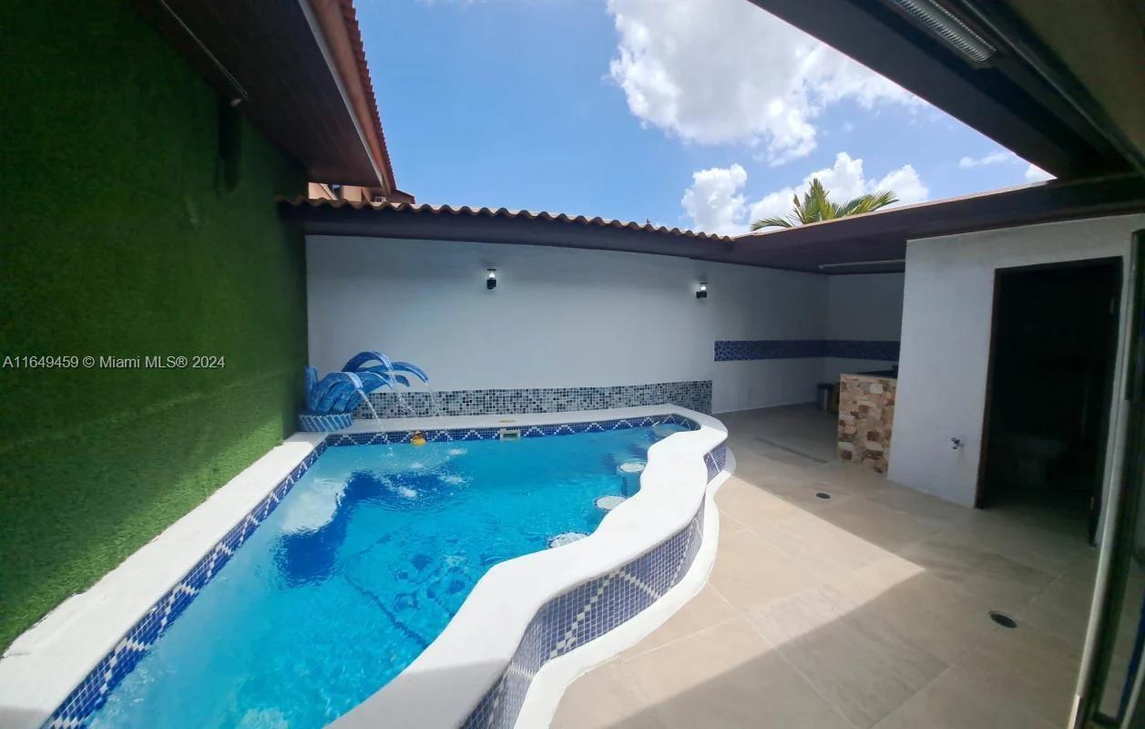 An outdoor patio features a curved swimming pool with blue tile accents and artificial turf — 56-D Versalles I - Panama City, PA Panama, PA