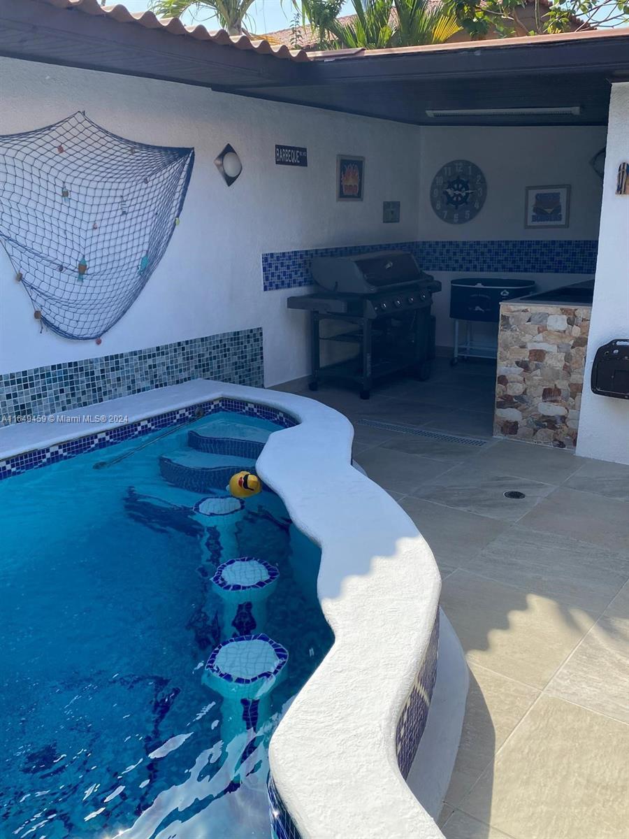 An outdoor patio features a swimming pool with built-in bar stools and a grilling area — 56-D Versalles I - Panama City, PA Panama, PA