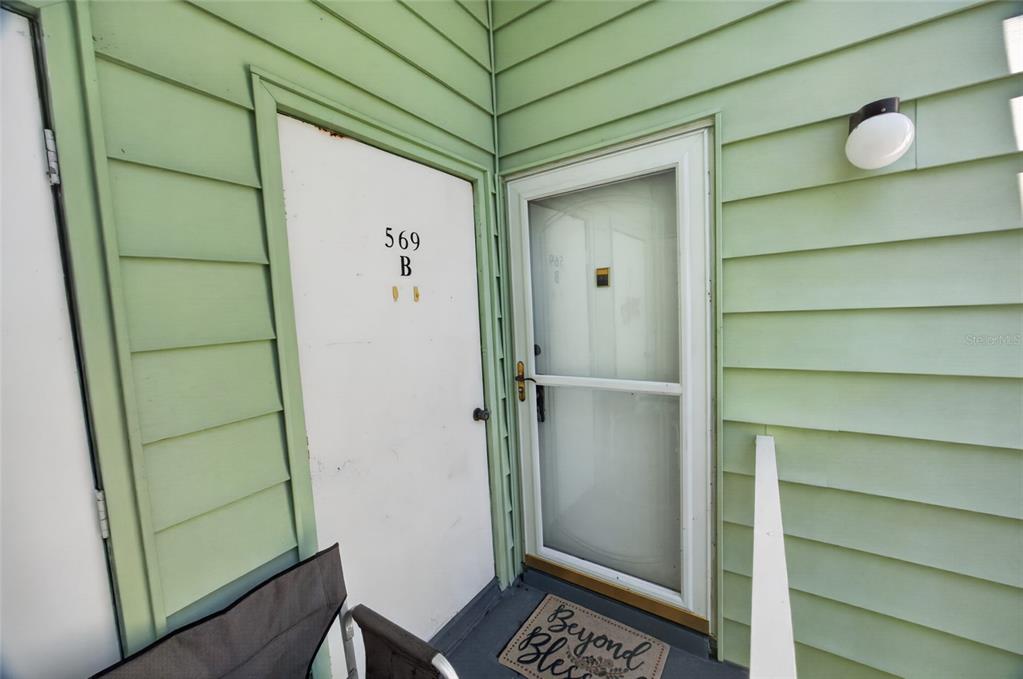 An exterior view shows a doorway with a screen door and a white door labeled 569B — 569 MIDWAY DRIVE UNIT B, OCALA, FL