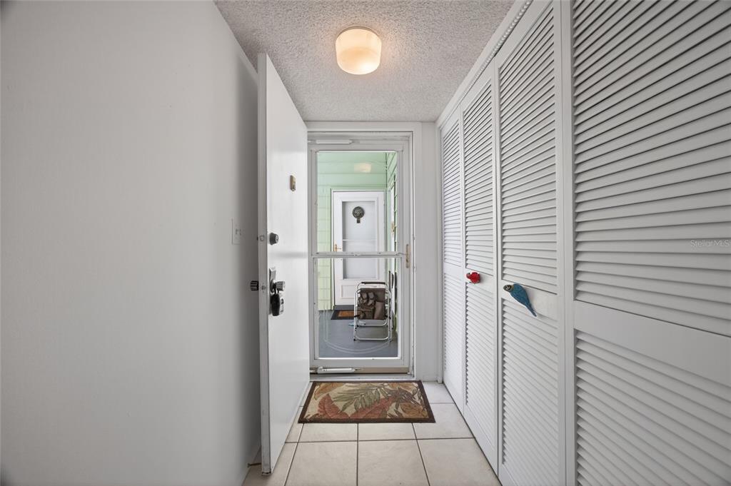 An entryway with white louvered closet doors, tile flooring, and a door leading to a porch — 569 MIDWAY DRIVE UNIT B, OCALA, FL