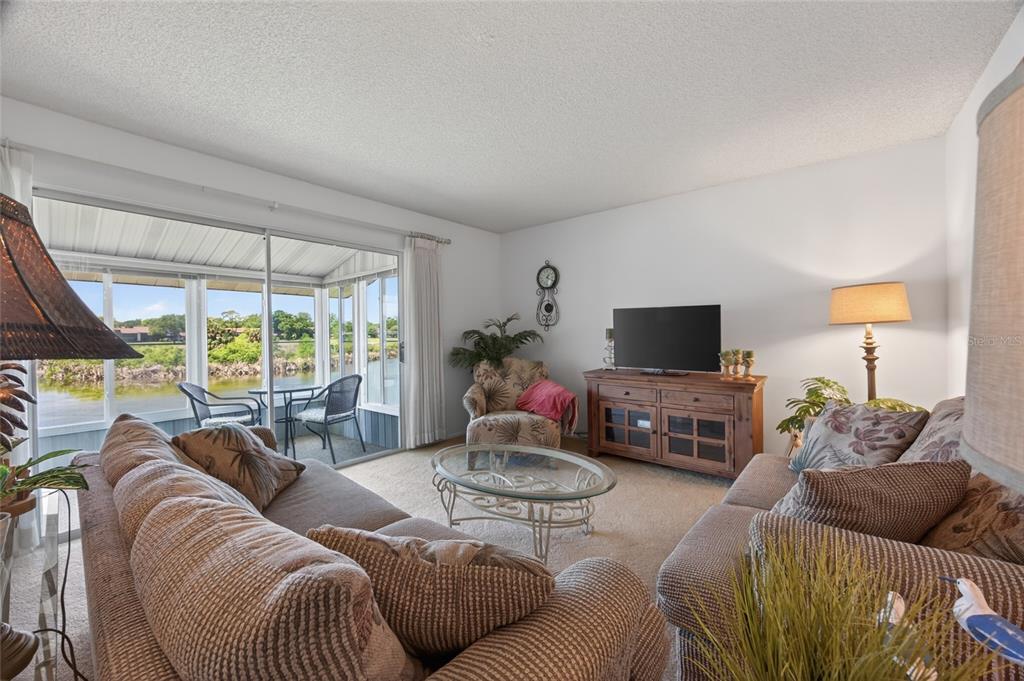 A living room features beige carpet, two sofas, a glass coffee table, and a sliding door — 569 MIDWAY DRIVE UNIT B, OCALA, FL