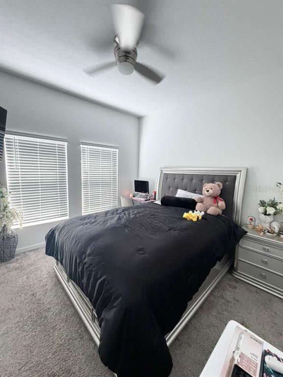 A bedroom features a gray tufted headboard, a black comforter, and two windows with blinds — 1103 POMELO STREET, DAVENPORT, FL