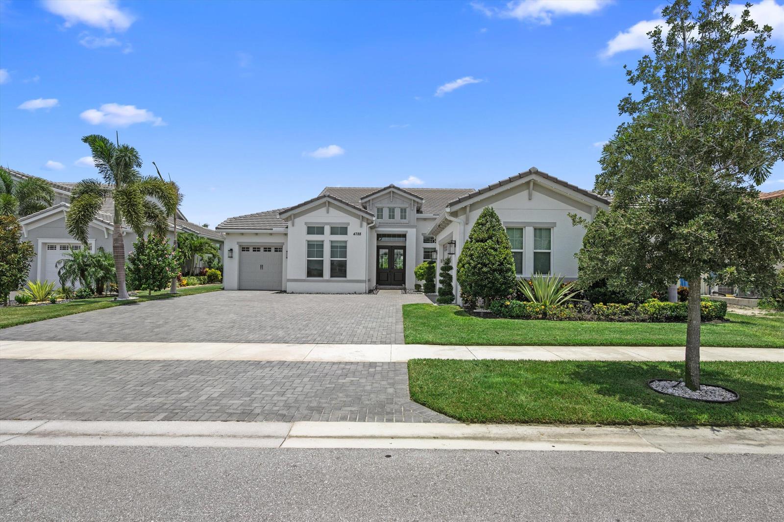 A single-story house with a paved driveway, a front lawn, and a palm tree — 4788 Estates Circle, Westlake FL 33470, WESTLAKE, FL