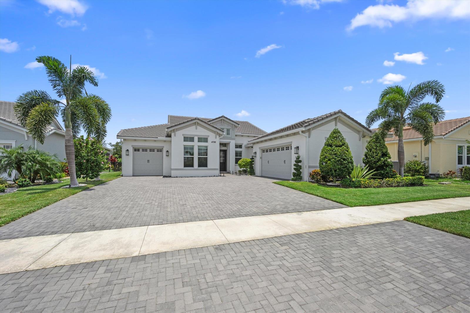 A single-story house with a paved driveway, two garages, and palm trees under a blue sky — 4788 Estates Circle, Westlake FL 33470, WESTLAKE, FL