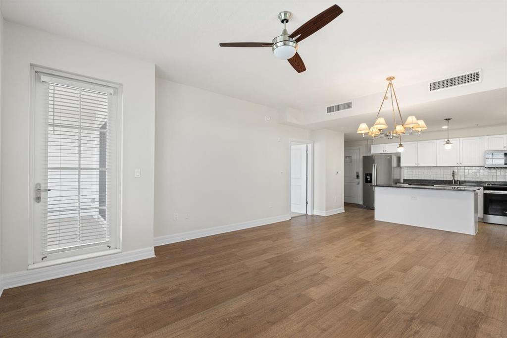 An open-concept living area features wood-look flooring, a ceiling fan, and an adjacent kitchen — 536 BAHIA BEACH BOULEVARD UNIT 236C, RUSKIN, FL