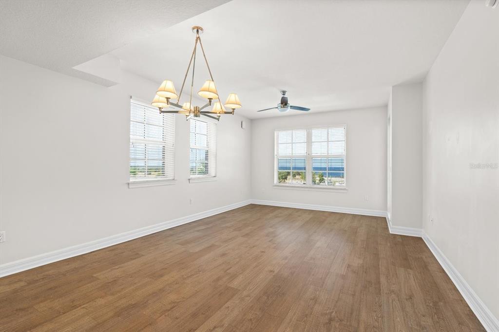 An empty room with wood-look flooring, a chandelier, a ceiling fan, and large windows — 536 BAHIA BEACH BOULEVARD UNIT 236C, RUSKIN, FL