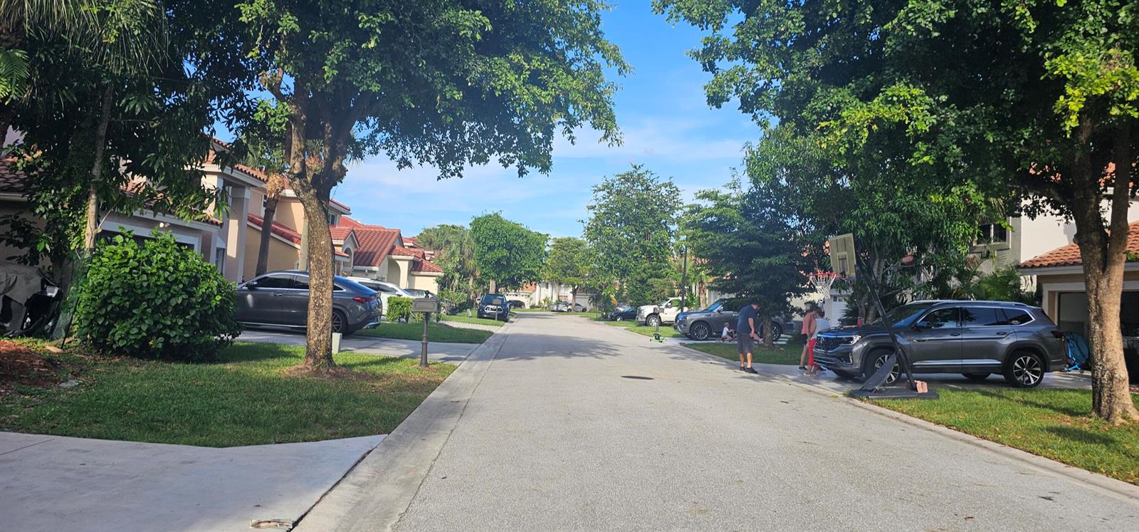 A suburban street lined with houses, mature trees, parked cars, and a basketball hoop — 10780 Cypress Lake Terrace, Boca Raton FL 33498, BOCA RATON, FL