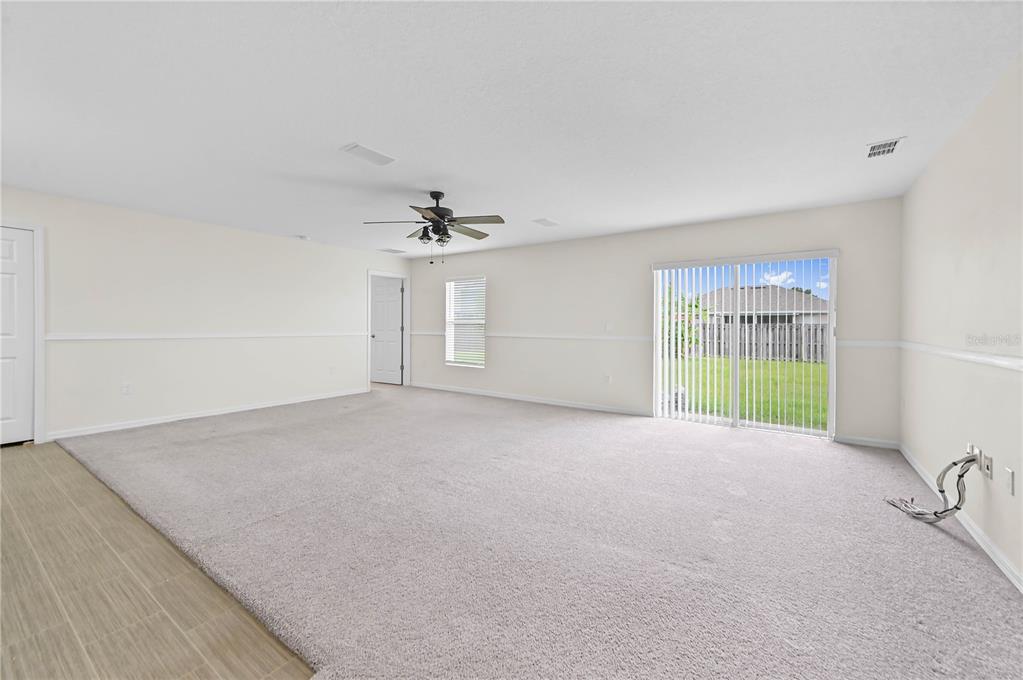 A spacious room with beige carpet, white walls, a ceiling fan, and sliding glass doors — 361 SW THORNHILL DRIVE, PORT ST LUCIE, FL