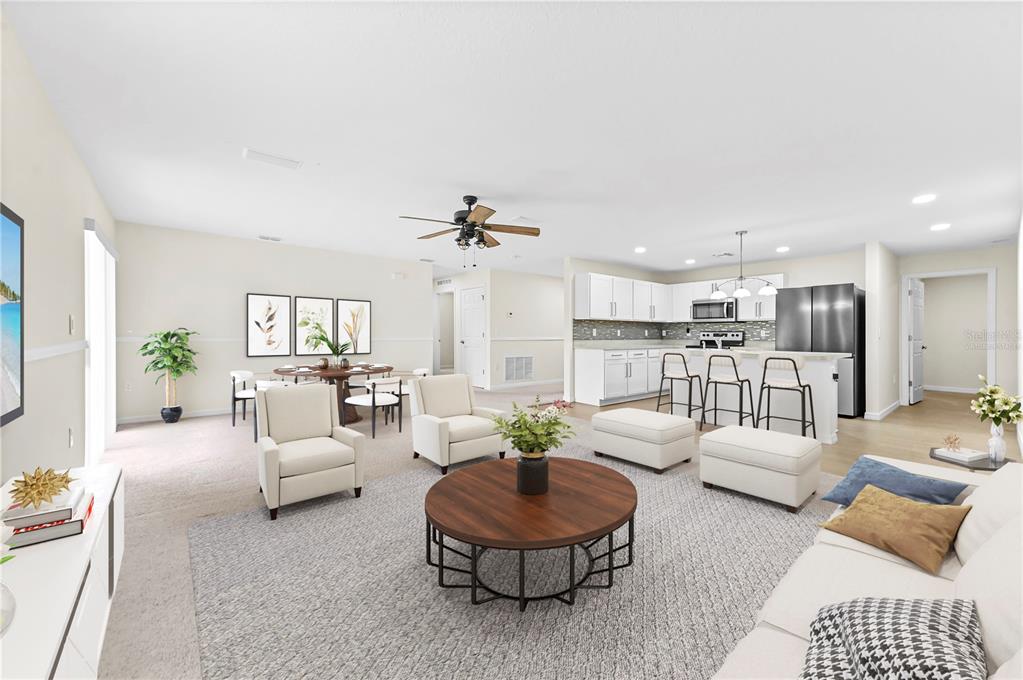 An open-concept living room and kitchen featuring white cabinetry, a round coffee table, and seating — 361 SW THORNHILL DRIVE, PORT ST LUCIE, FL