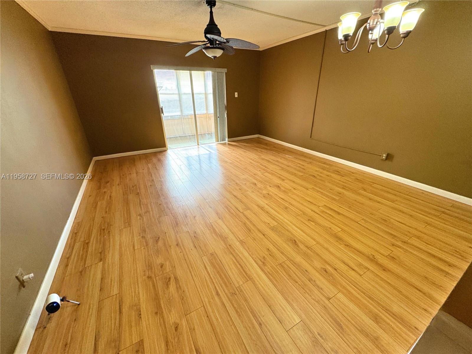 A room with brown walls, wood-look flooring, a ceiling fan, and a sliding glass door — 2060 NW 48th Ter # 308, Lauderhill FL 33313, LAUDERHILL, FL