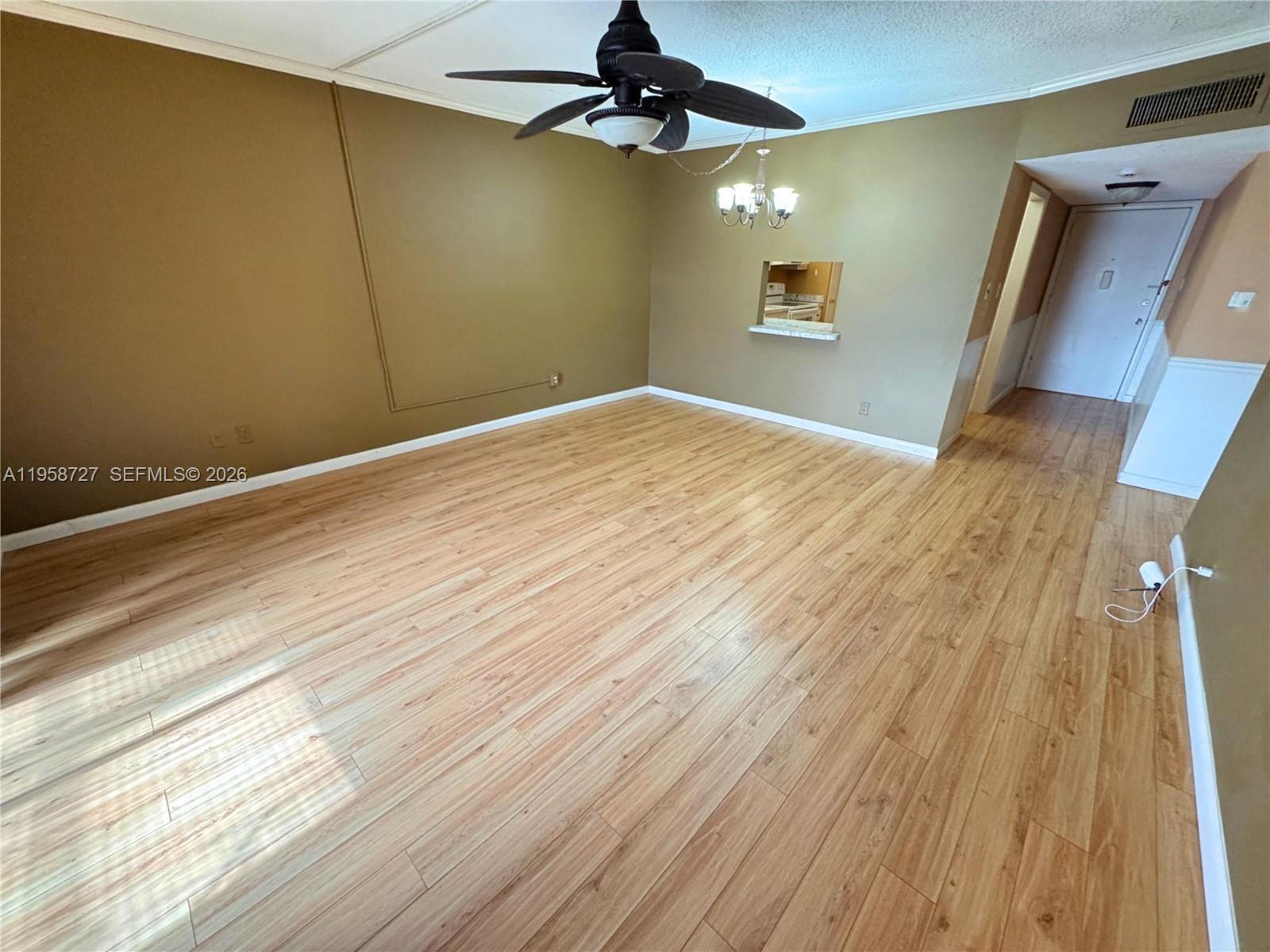 An empty room features light wood-look flooring, tan walls, a ceiling fan, and a pass-through window — 2060 NW 48th Ter # 308, Lauderhill FL 33313, LAUDERHILL, FL