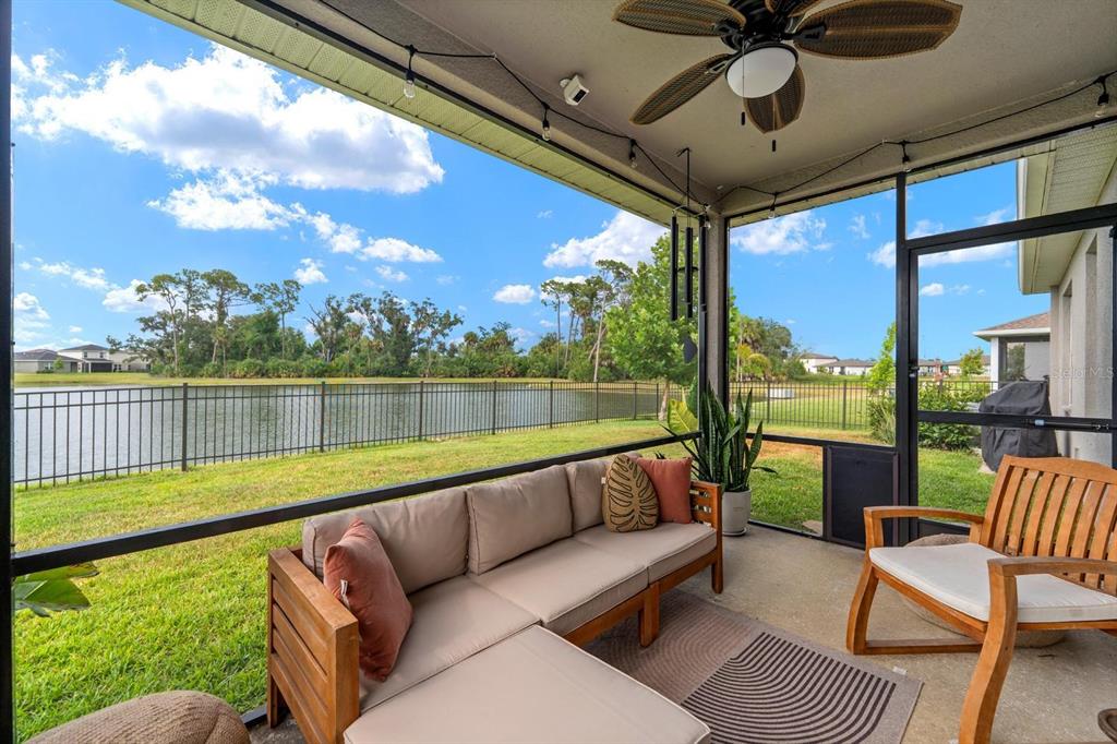A screened-in patio features a sectional sofa, a wooden chair, and a view of a lake — 10024 EVENTIDE TRAIL, PARRISH, FL