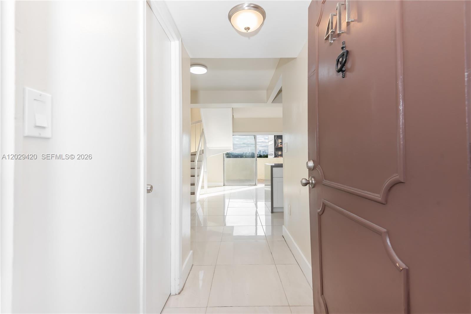 A view from an open doorway into a tiled entryway leading toward a staircase — 300 NW 42nd Ave # 411, Miami FL 33126, MIAMI, FL