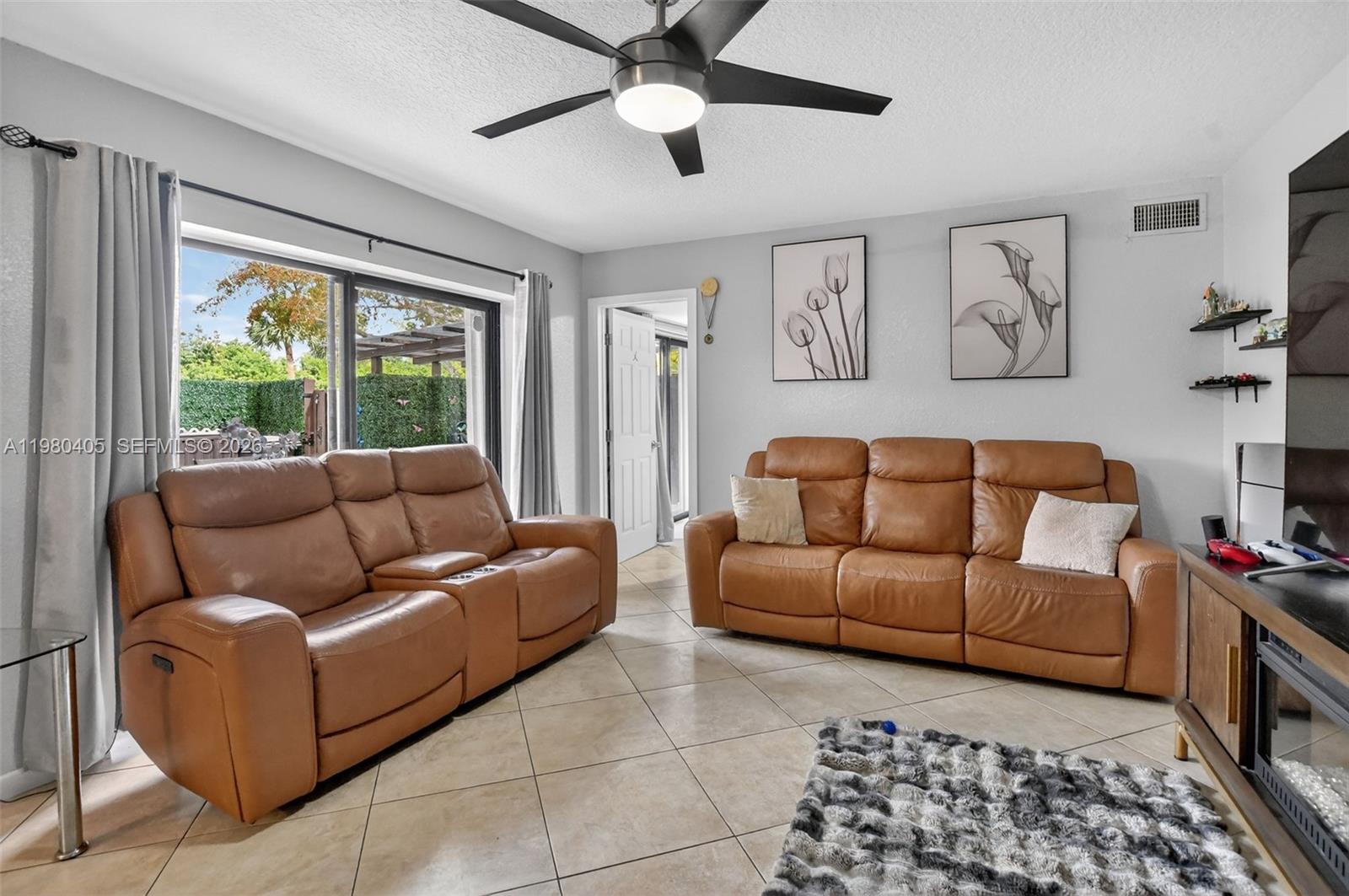 A living room features two tan leather sofas, tile flooring, and a sliding glass door — 8181 Boca Rio Dr # 8181, Boca Raton FL 33433, BOCA RATON, FL