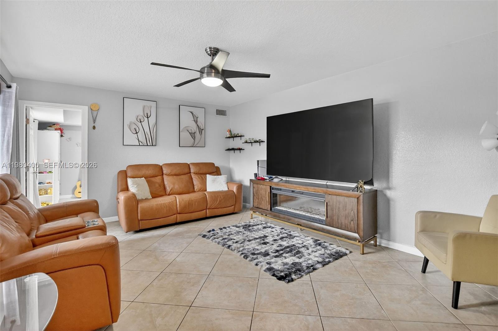 A living room features a large television, leather sofas, tile flooring, and a ceiling fan — 8181 Boca Rio Dr # 8181, Boca Raton FL 33433, BOCA RATON, FL