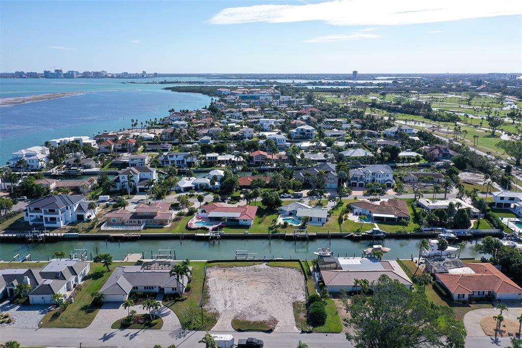 An aerial view shows a vacant waterfront lot situated between residential homes along a canal — 536 GUNWALE LANE, LONGBOAT KEY, FL