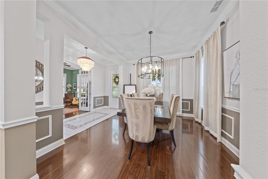 A dining room features a dark wood table, upholstered chairs, a chandelier, and hardwood floors — 11617 CAMDEN PARK DRIVE, WINDERMERE, FL
