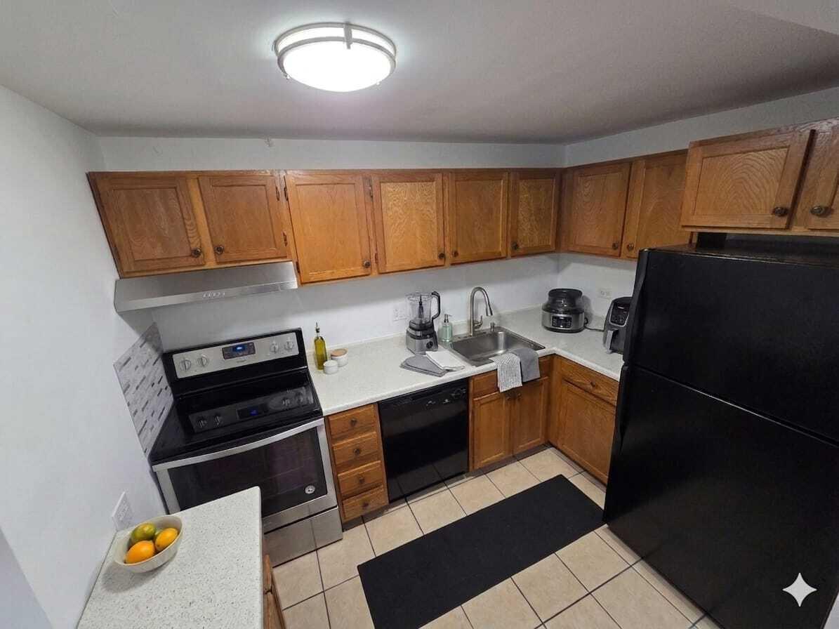 A kitchen with wood cabinets, stainless steel appliances, a black refrigerator, and tile flooring — 3670 Inverrary Drive # 3y, Lauderhill FL 33319, LAUDERHILL, FL