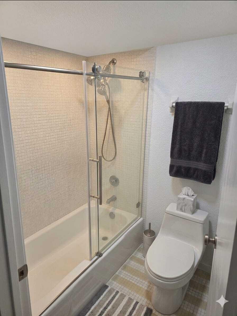 A small bathroom features a bathtub with a glass sliding door and a white toilet — 3670 Inverrary Drive # 3y, Lauderhill FL 33319, LAUDERHILL, FL