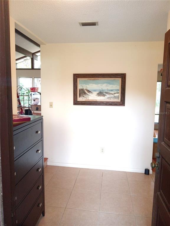 An entryway with tile flooring, a dark dresser, and a framed beach painting on the wall — 8136 NW 5TH COURT, GAINESVILLE, FL
