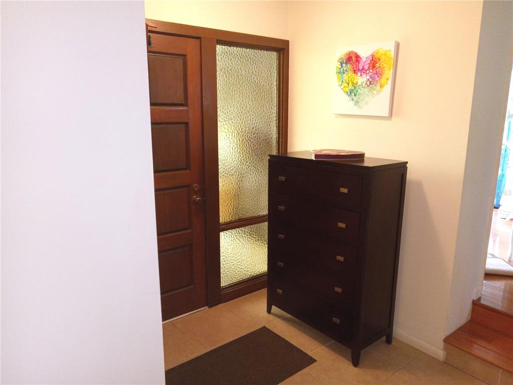 An entryway features a wooden door with a textured glass panel and a dark dresser — 8136 NW 5TH COURT, GAINESVILLE, FL