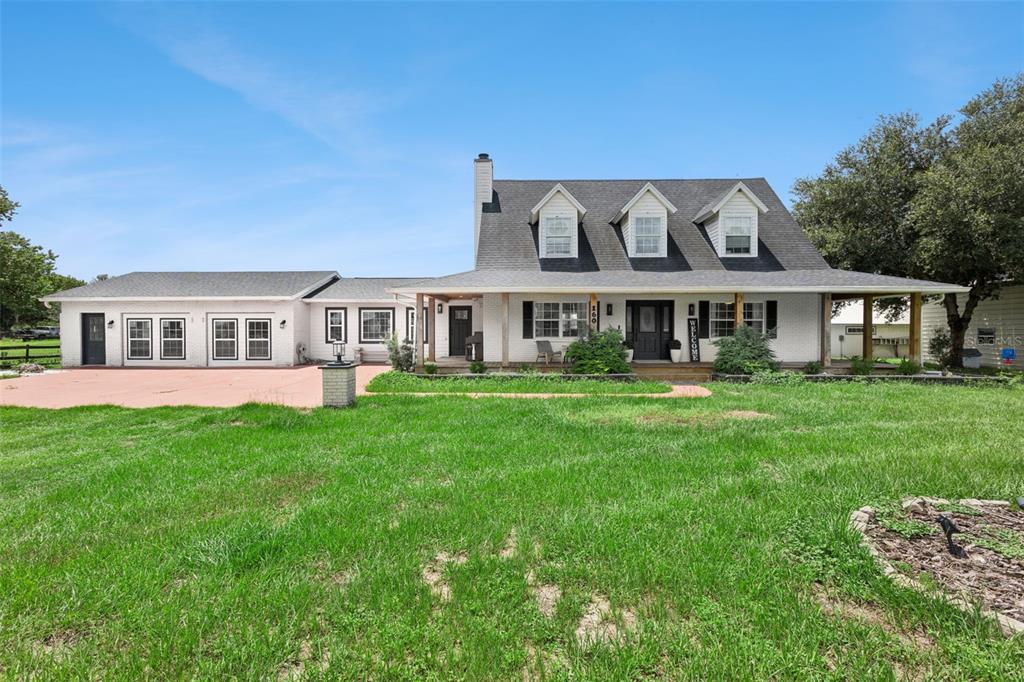 A white, two-story farmhouse with a dark roof, dormer windows, and a covered front porch — 160 JUNIPER TRAIL, OCALA, FL