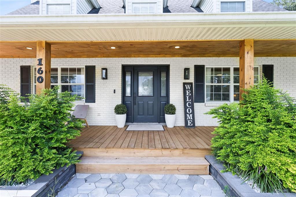 A white brick house features a wooden porch, dark shutters, and a central front door — 160 JUNIPER TRAIL, OCALA, FL