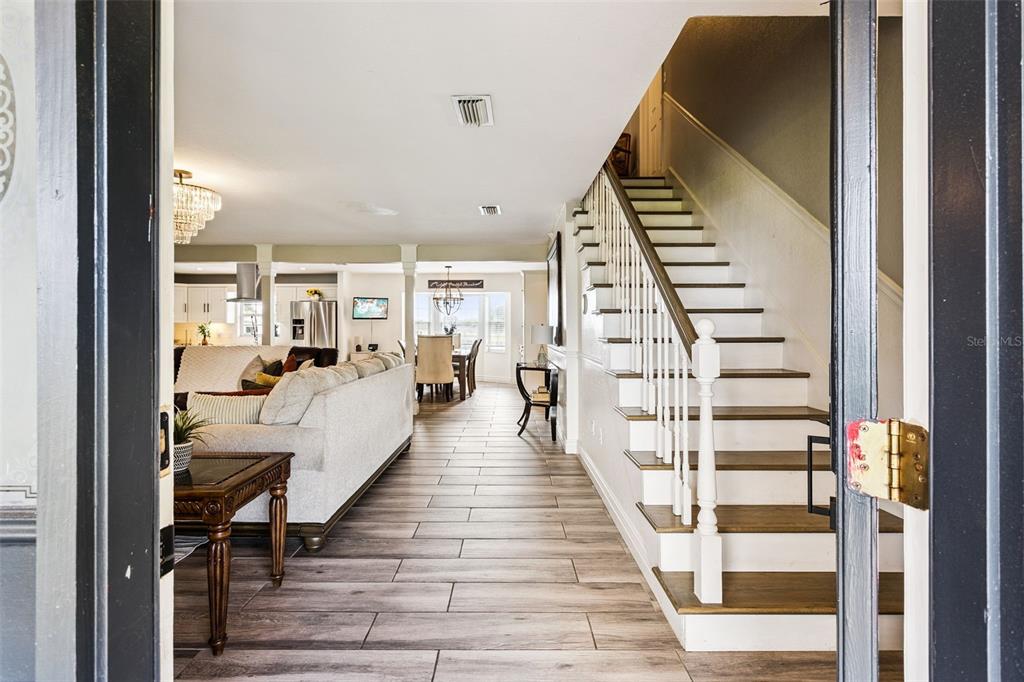 An entryway view shows a staircase, light wood-look tile flooring, and an open-concept living area — 160 JUNIPER TRAIL, OCALA, FL