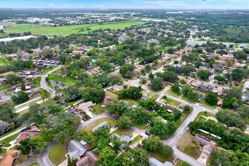 An aerial view shows a suburban neighborhood with houses, green trees, and winding roads — 7604 S SANIBEL DRIVE, TAMPA, FL