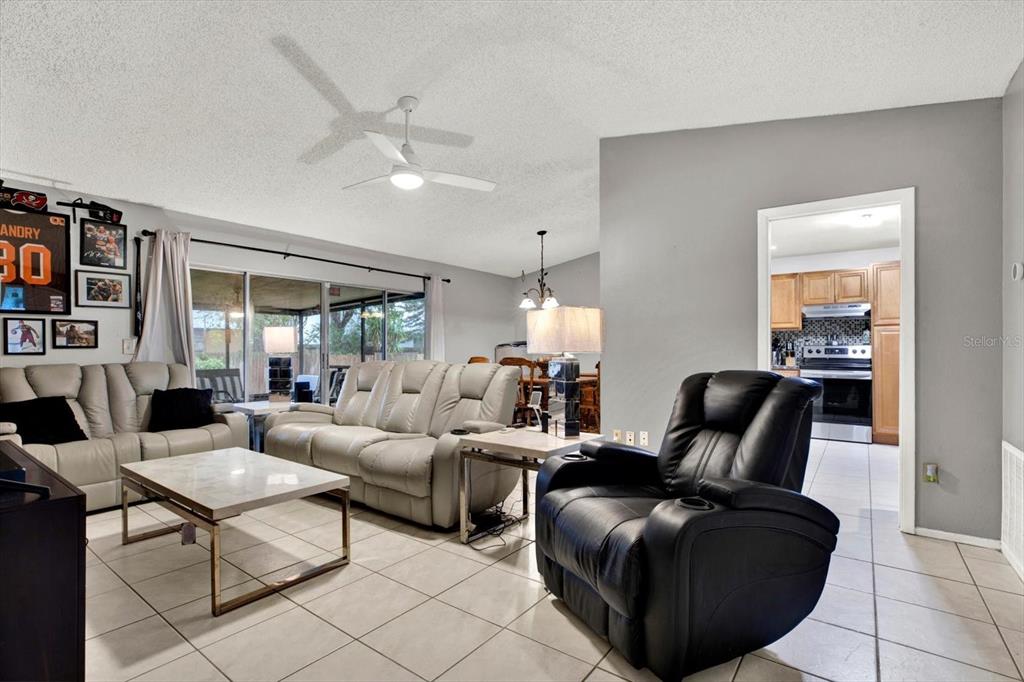 A living room with light tile floors, a black recliner, and a beige sofa set — 7604 S SANIBEL DRIVE, TAMPA, FL