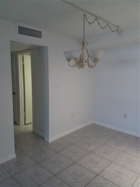 A dining area features light-colored tile flooring, white walls, and a hanging chandelier — 4854 MARINE PARKWAY UNIT 103, NEW PORT RICHEY, FL