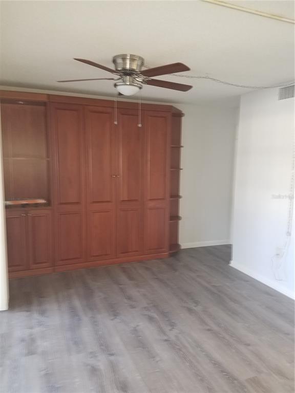 A room features wood cabinetry, a ceiling fan, and gray wood-look flooring — 4854 MARINE PARKWAY UNIT 103, NEW PORT RICHEY, FL