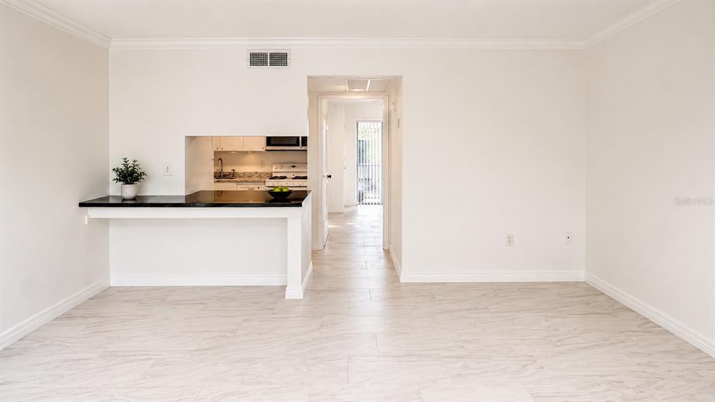 A living area features light tile flooring, a breakfast bar, and a view into the kitchen — 120 BLUE POINT WAY UNIT 170, ALTAMONTE SPRINGS, FL