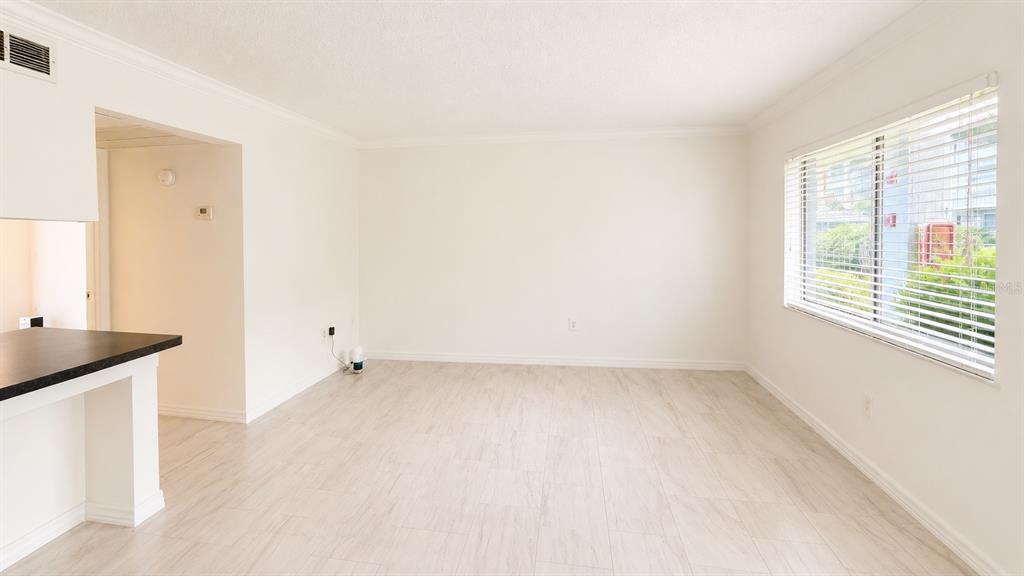 A bright, empty living room features light-colored wood-look tile flooring and a large window — 120 BLUE POINT WAY UNIT 170, ALTAMONTE SPRINGS, FL