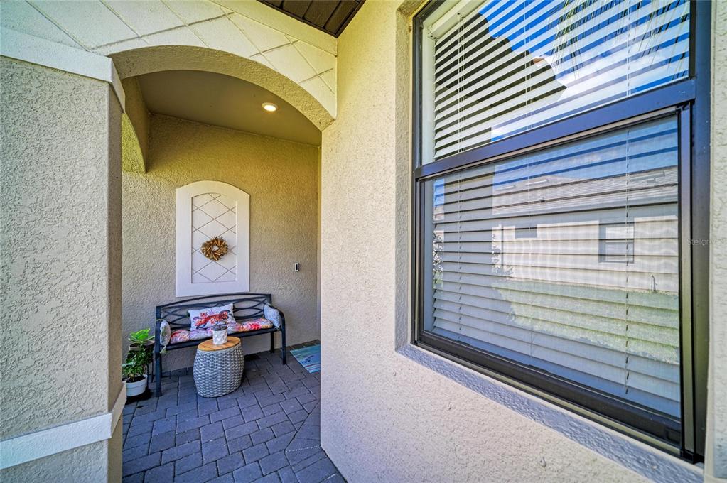 A covered entryway features a paved floor, a small bench, and a large window — 15308 SUNNY DAY DRIVE, BRADENTON, FL