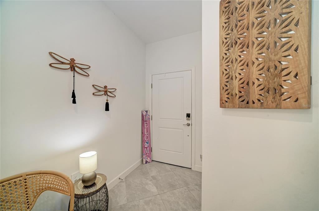 A bright entryway features tiled floors, a white door, and decorative wall art — 15308 SUNNY DAY DRIVE, BRADENTON, FL