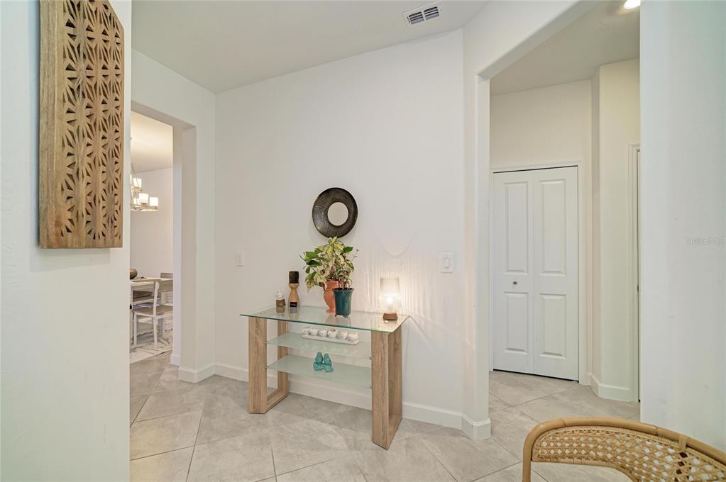 A glass-topped console table sits in a tiled entryway with a wall-mounted wooden art piece — 15308 SUNNY DAY DRIVE, BRADENTON, FL