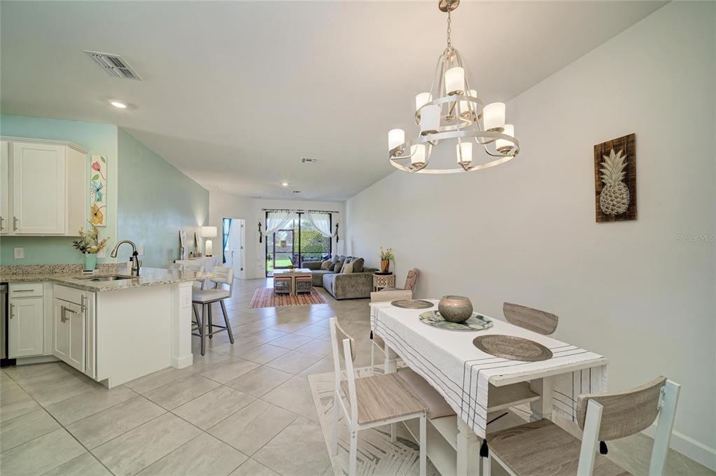 An open-concept kitchen, dining area, and living room feature tile flooring and a chandelier — 15308 SUNNY DAY DRIVE, BRADENTON, FL