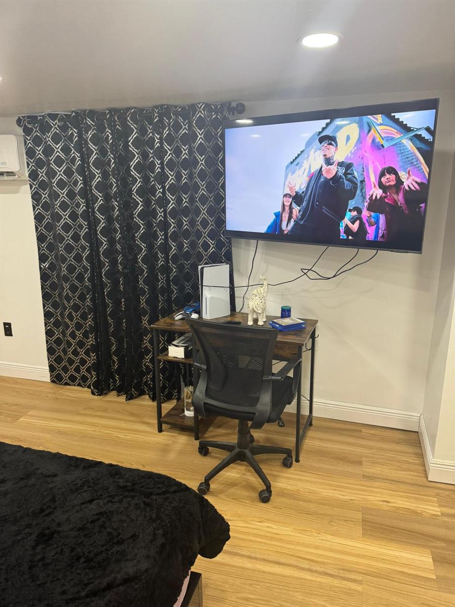 A bedroom features a wall-mounted television, a desk with a gaming console, and patterned curtains — 187 Montura Avenue, Clewiston FL 33440, CLEWISTON, FL