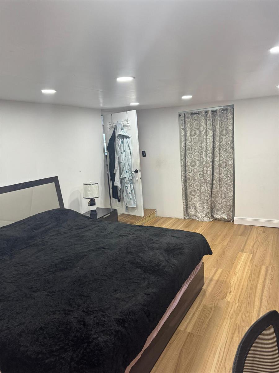 A bedroom features a black bed, wood-look flooring, recessed lighting, and a curtained closet area — 187 Montura Avenue, Clewiston FL 33440, CLEWISTON, FL
